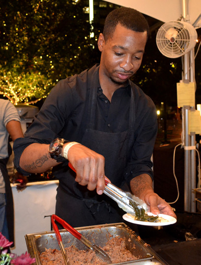 One of Chef Wilcox’s team members serving up their delicous collard greens, smothered pork and smooth peppery grits.