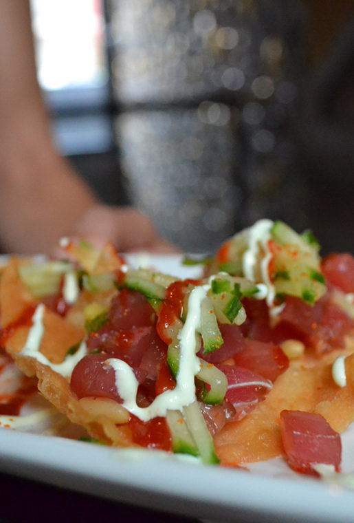 Extra pretty Tuna Poke Nachos are wonderful, topped with wasabi crema, pine nuts and cucumber on extra crispy wontons.